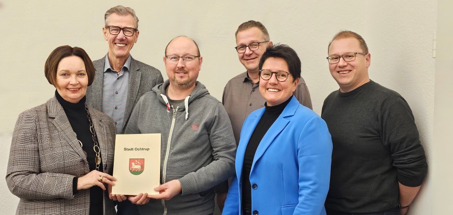 Sie sehen: ein Gruppenfoto mit Bürgermeisterin Christa Lenderich, Kämmerer Roland Frenkert, Wehrführer Andreas Leusing, Fachbereichsleiter Holger Brüggemann, die Erste Beigeordnete Birgit Stening und Lars Wiggenhorn aus der zuständigen Verwaltungsabteilung.