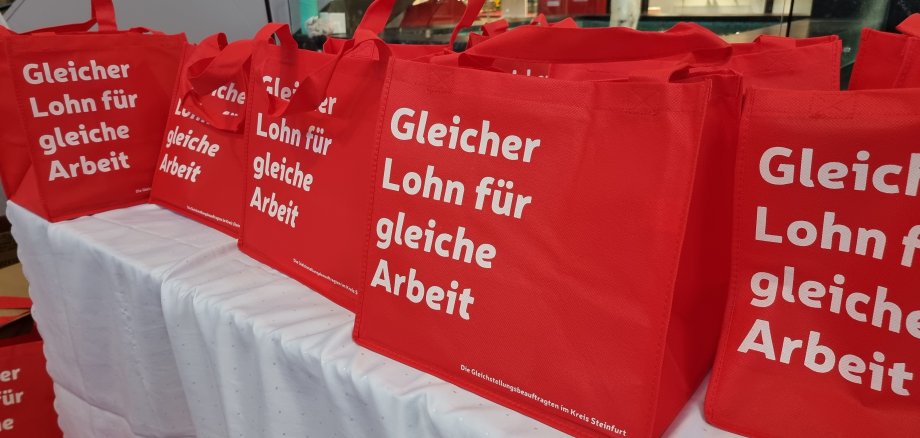 Sie sehen: rote Taschen den Equal Pay Day mit der Aufschrift: "Gleicher Lohn für gleiche Arbeit"