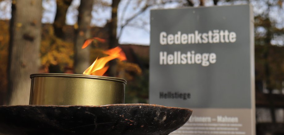 Infostele mit Fackel am Eingang der Gedenkstätte Hellstiege