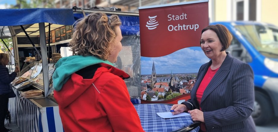 Sie sehen: Zwei Personen im Gespräch an einem Stehtisch: Bürgermeisterin Christa Lenderich auf der Wochenmarktsprechstunde