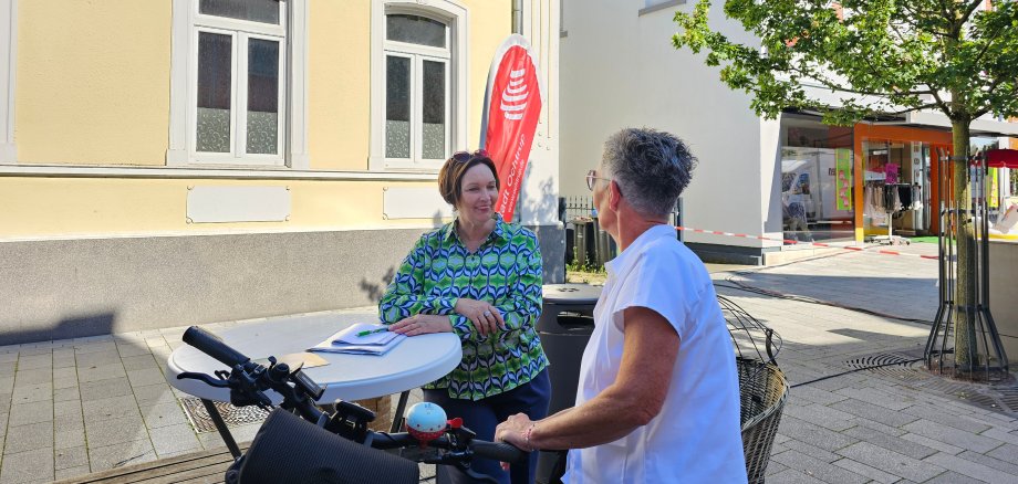 Sie sehen: Bürgermeisterin Christa Lenderich mit einer Passantin an einem Stehtisch in der Fußgängerzone